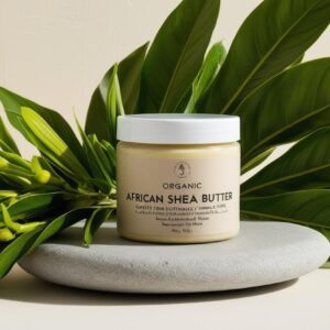 “Organic African shea butter in eco-friendly jar, placed on a neutral stone slab with green leaves beside, clean natural background, luxury skincare aesthetic”