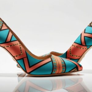 “Pair of high-heeled shoes covered in vibrant Ankara fabric, angled to show detail, centered on a clean white background, shadow-free, product fashion photography style